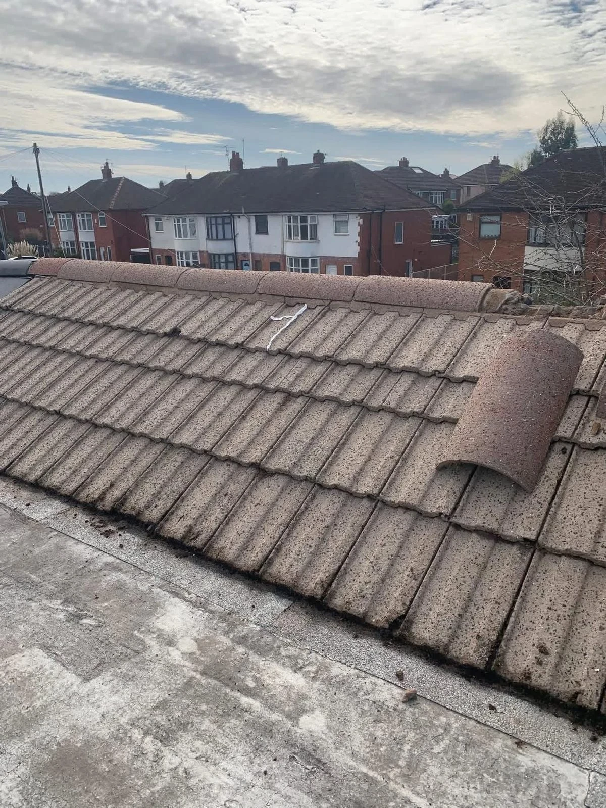 Older concrete tiled roof with a displaced ridge tile before repairs