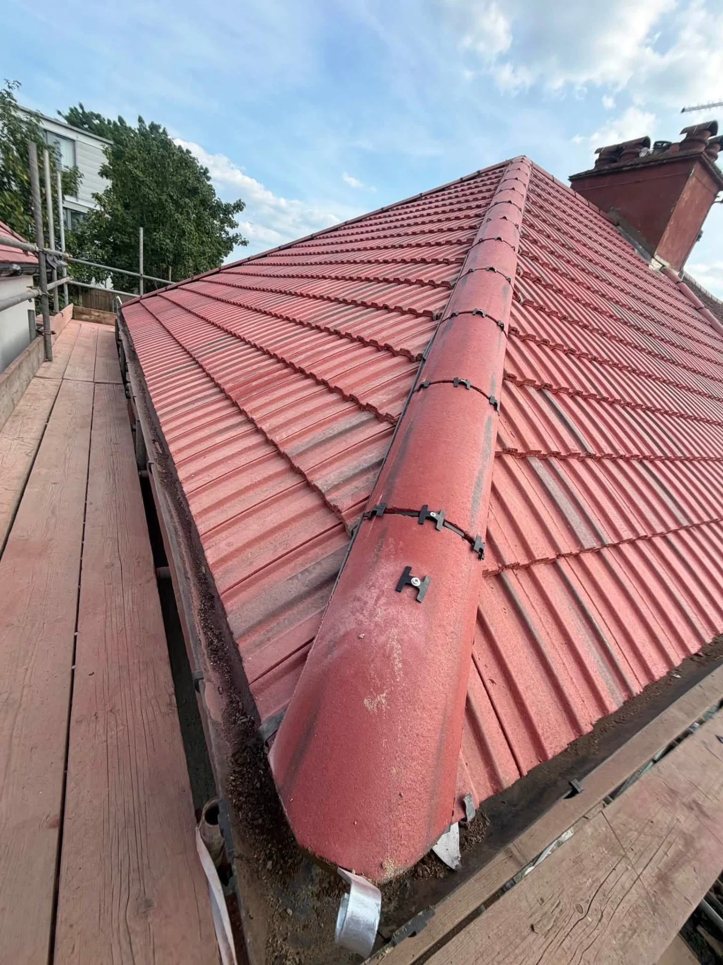 Close view of mechanically secured red ridge tiles along a roof hip