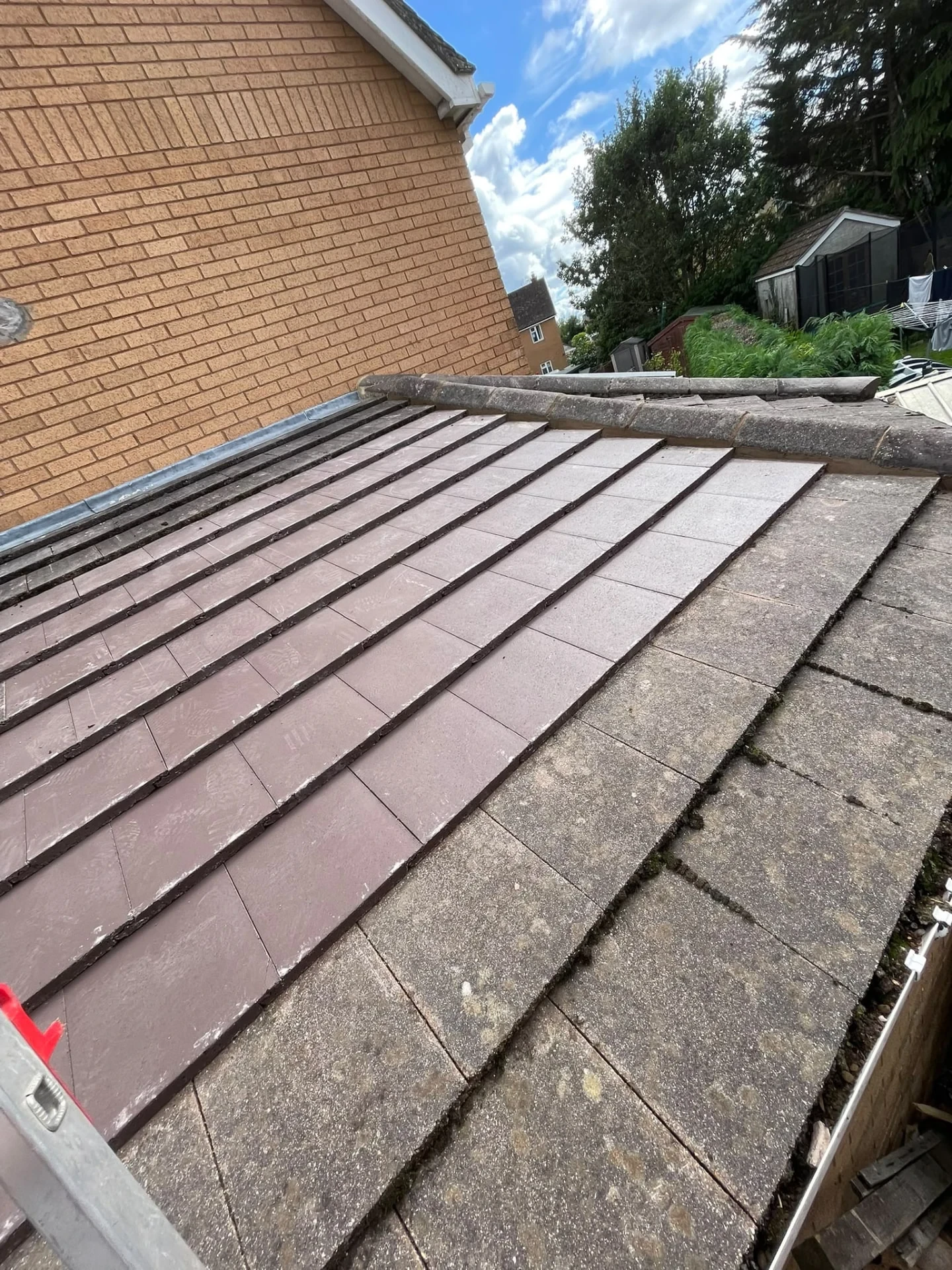 Roof repair work at the junction of a tiled lower roof and brick wall