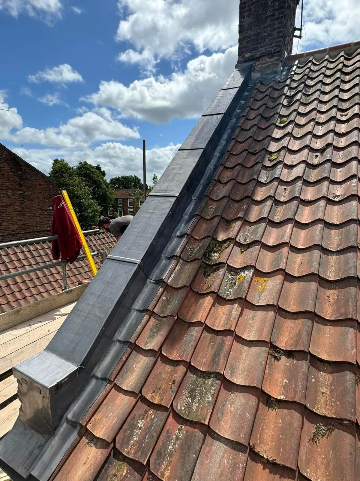Lead covering along a pitched roof verge adjoining a brick chimney