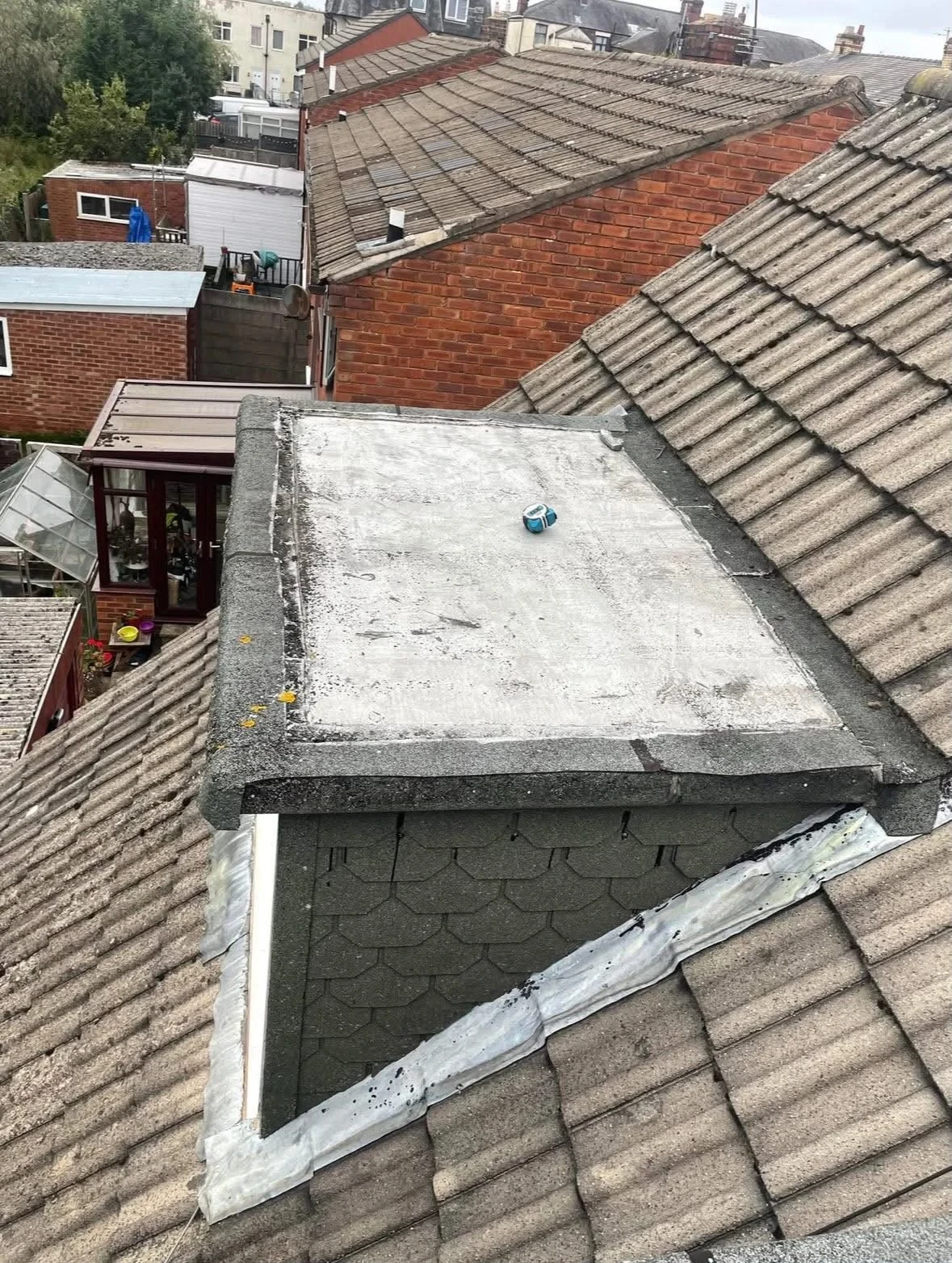 Weathered flat dormer roof covering before flat roof repairs