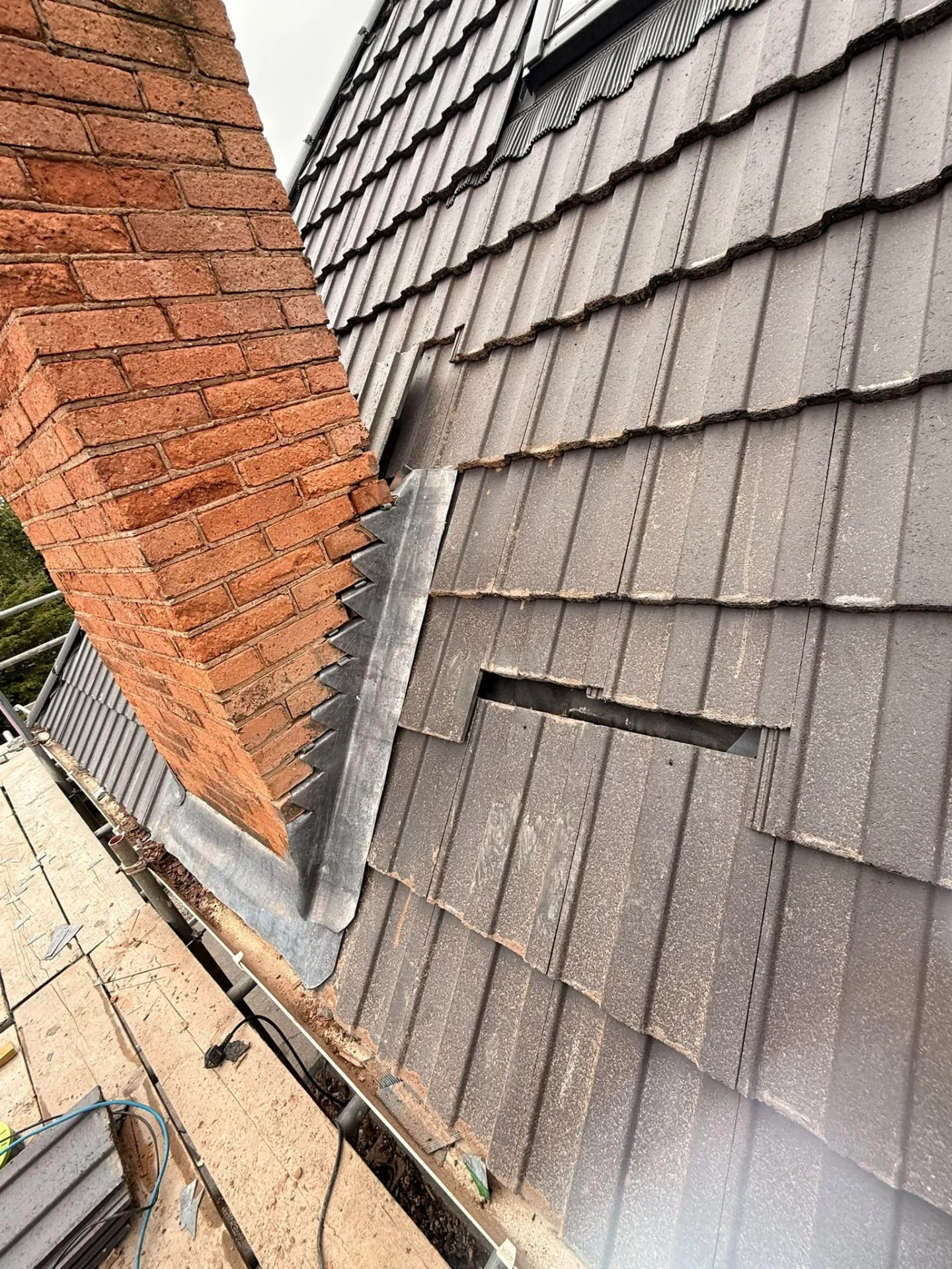 Brick chimney and adjoining roof tiles during chimney maintenance