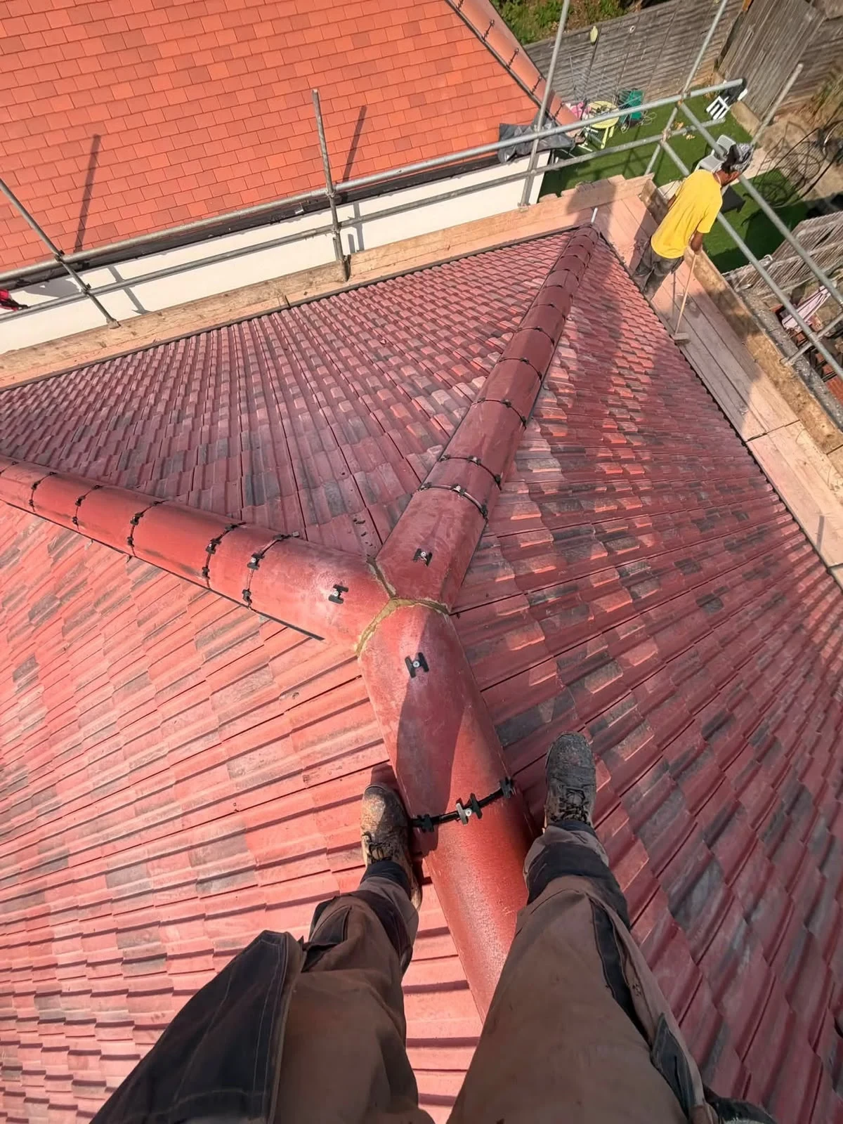 Red dry ridge tiles on a scaffolded pitched roof