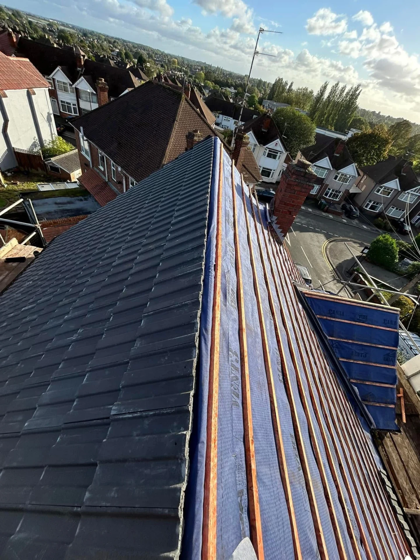 Partially tiled pitched roof with exposed timber battens during roofing work