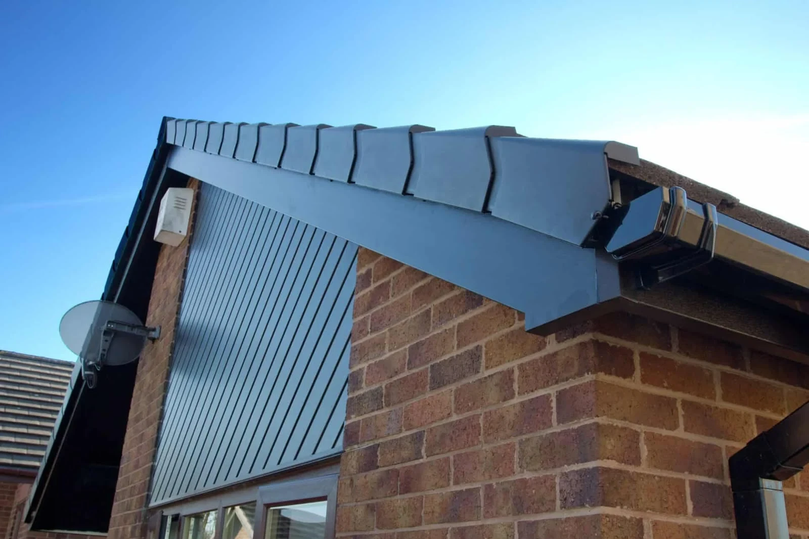Grey uPVC roofline cladding and fascia boards beneath the tiled gable edge