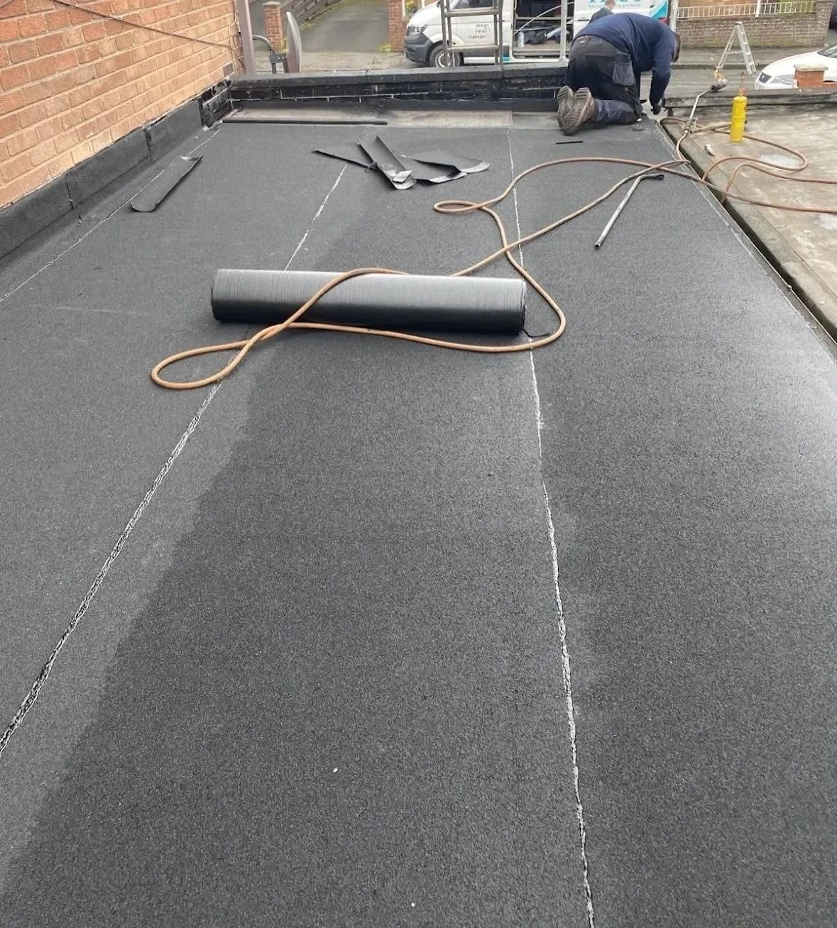 Flat roof membrane installation with a roller and tools during roofing work