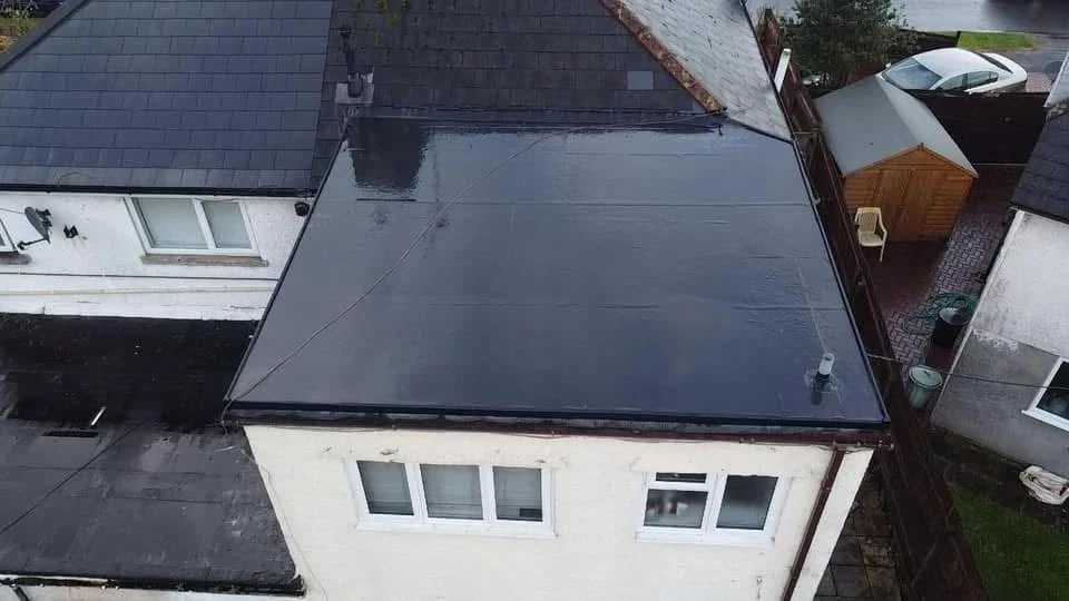 Completed dark flat roof above a white rendered extension