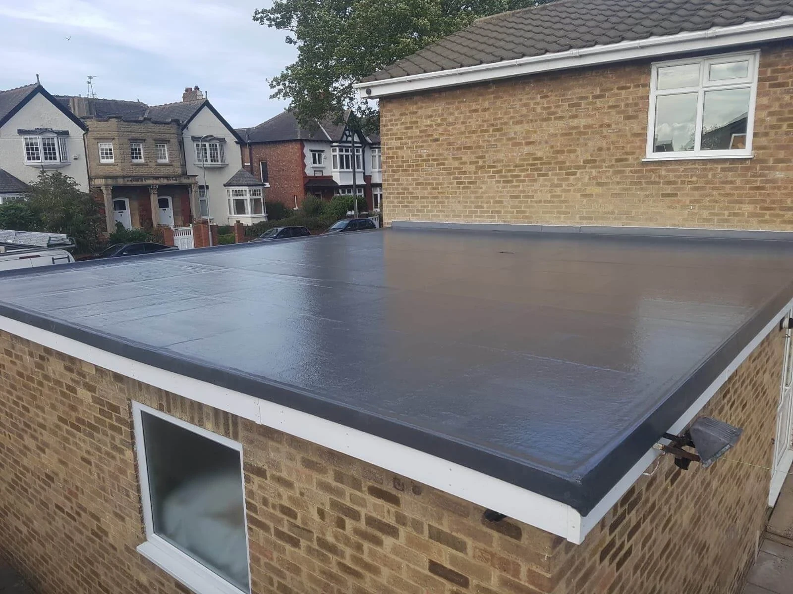 Finished dark flat roof on a brick extension with neat perimeter edging